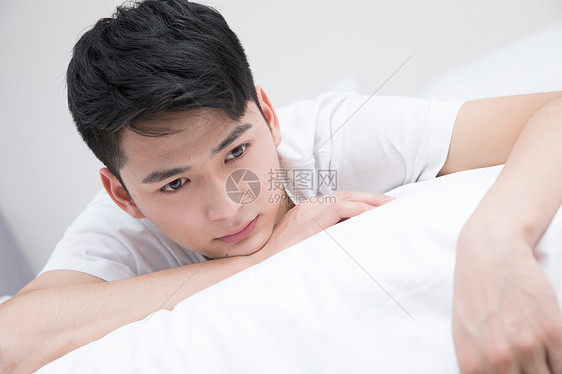 年轻男性沮丧地躺在床上图片