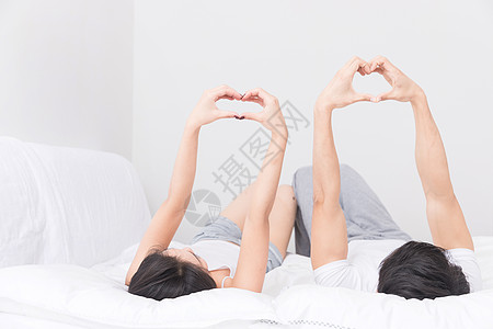 比心可爱情侣年轻夫妻躺床上比心背景