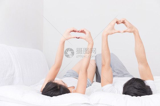 年轻夫妻躺床上比心图片