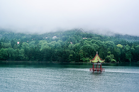 烟雾森林绵绵细雨中坐落在湖中的小亭子背景