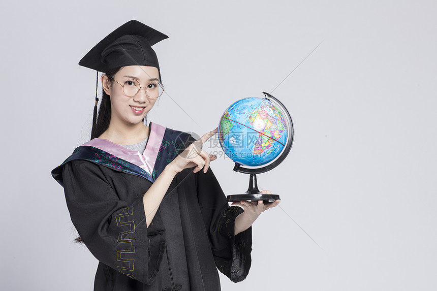 拿着地球仪的毕业女大学生图片