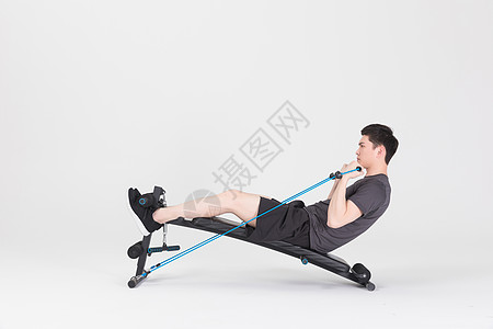 多功能仰卧板坐在运动器械上拉阻力带的健身男性背景