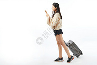 年轻女孩拖着行李箱用手机找路图片