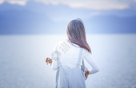 女孩谈尤克里里女孩在海边玩耍背影背景