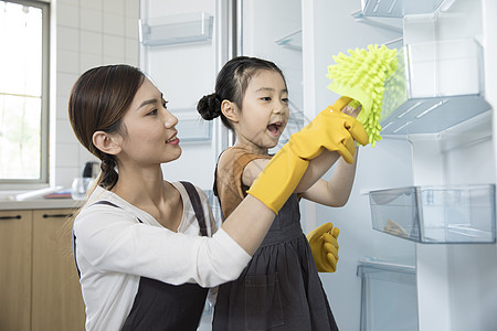 春节扫尘妈妈和女儿在新家清洁冰箱背景