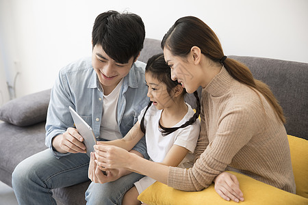 一家人在新家沙发上看平板电脑图片