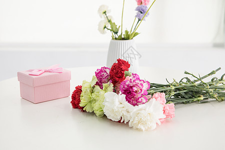 桌子上的康乃馨与礼盒图片