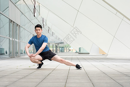 年轻男性户外运动热身压腿拉伸动作图片
