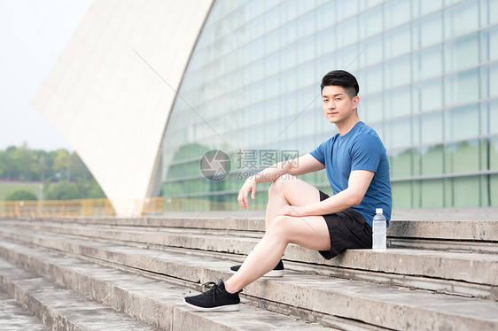 运动后坐着休息喝水放松的年轻男性