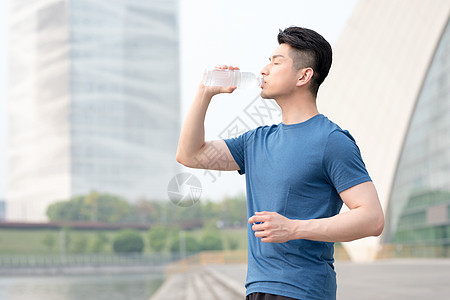 健康男性运动健身后站着喝水的年轻男性背景