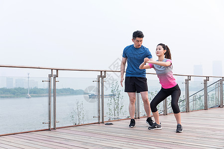 健身指导教练指导年轻女子热身运动户外锻炼背景