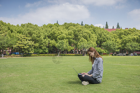 电脑考试女学生在草坪上学习背景