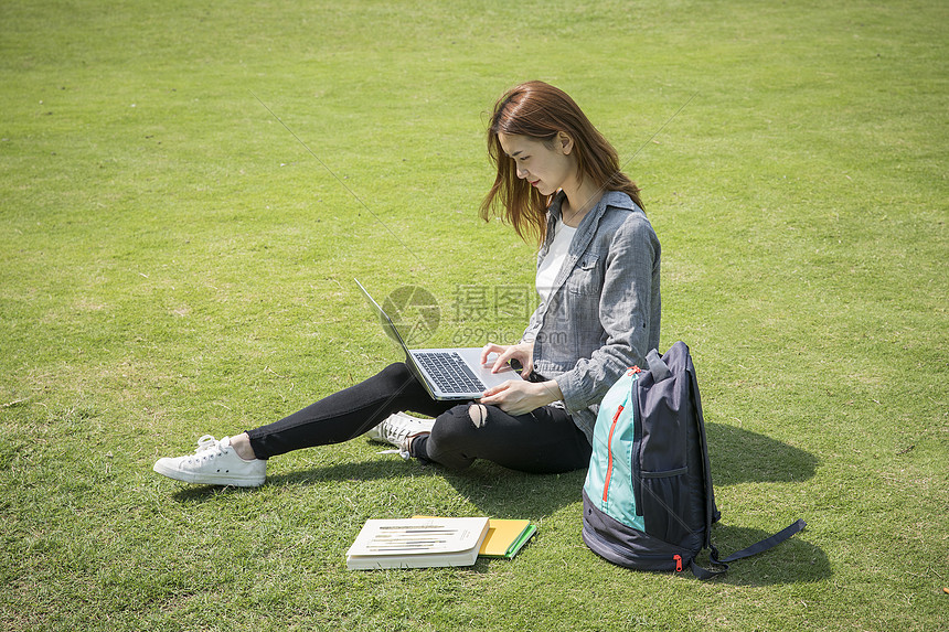 女学生在大学草坪上看电脑图片