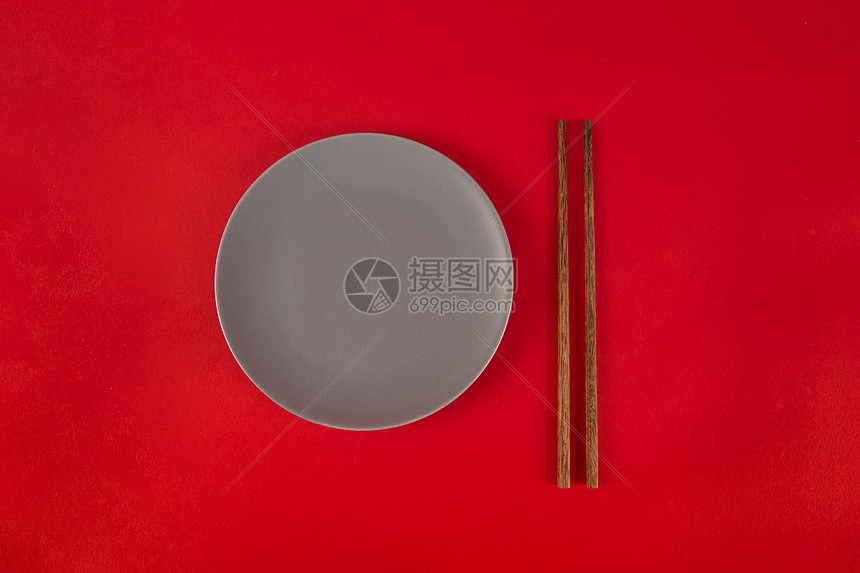 红色背景上的筷子与盘子图片