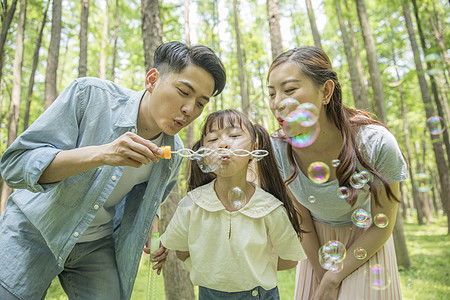 幸福一家人一家人在森林公园吹泡泡背景