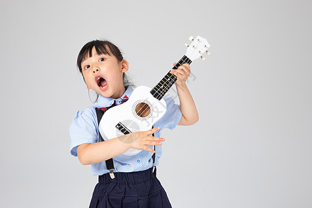 孩子吉他弹尤克里里高声唱歌的小女孩背景