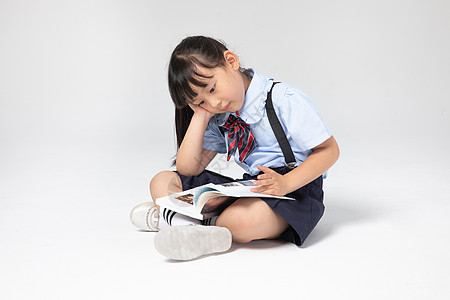 穿棉袄的小女孩穿校服的小女孩在看书背景