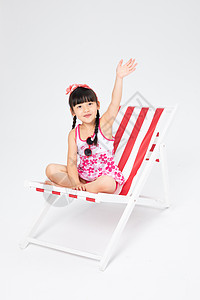 沙滩椅上的挥手的泳装小女孩图片