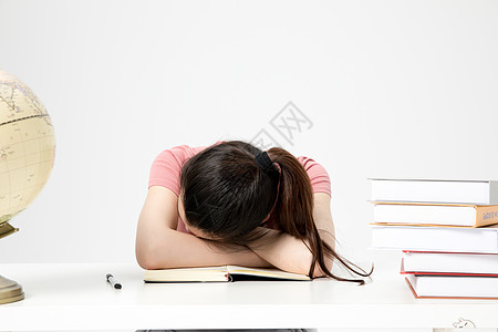 青年女性学生课桌上睡觉休息图片
