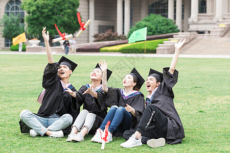 穿学士服坐在开心坐在草地上的大学生高清图片
