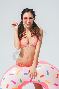 穿粉色比基尼的可爱女生拿着泳圈背景图片