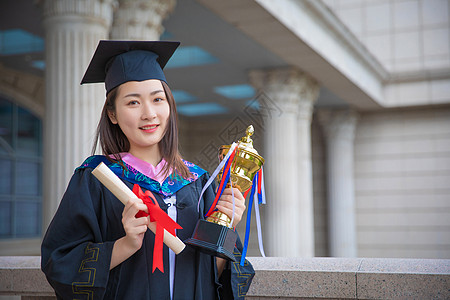 大学毕业奖杯微笑毕业生手拿着奖杯和证书背景