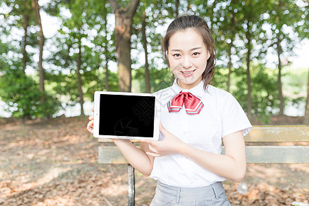 学院风女生林荫道拿平板电脑图片