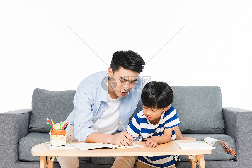 沙发上父亲辅导孩子写作业图片