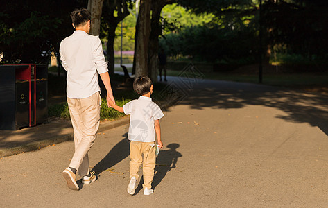 爸爸和孩子公园里牵手散步父子背影背景