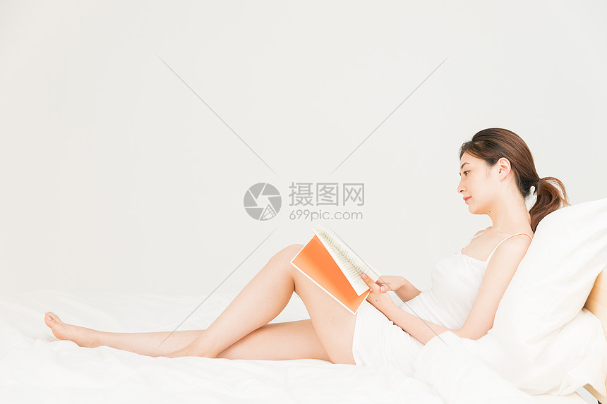 年轻女性床上看书图片