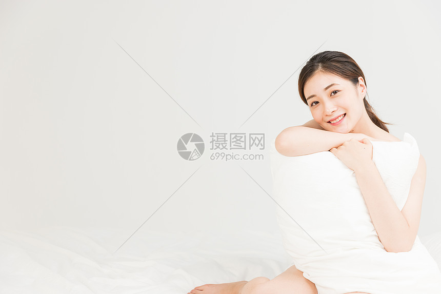 年轻女性床上抱着枕头放松图片