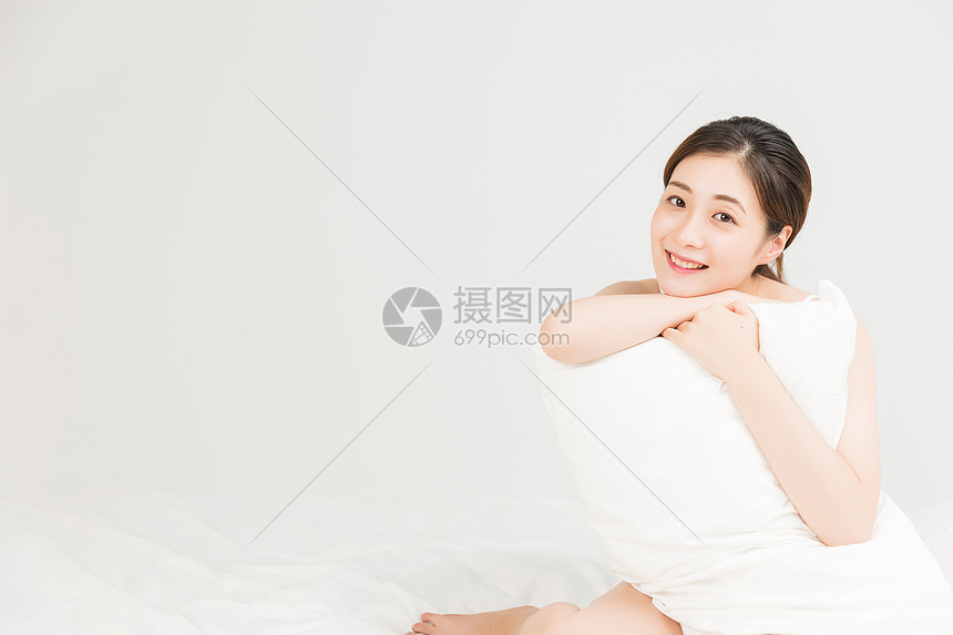 年轻女性床上抱着枕头放松图片