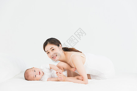 母婴妈妈在床上逗宝宝开心成长高清图片素材
