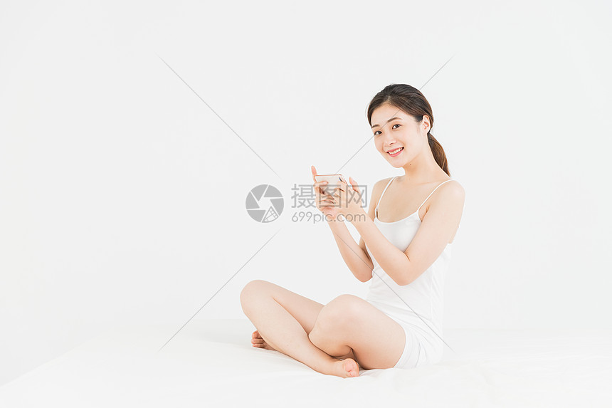 年轻女性床上玩手机图片