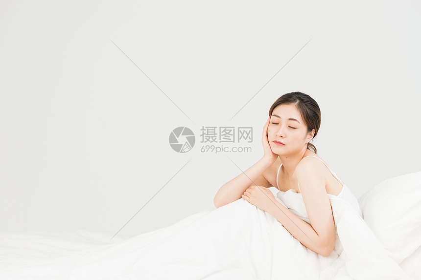 年轻女性坐床上休息图片