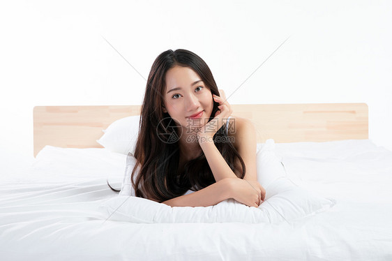 年轻女性趴在床上玩图片