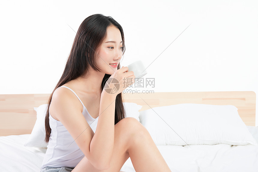 年轻女孩坐在床上喝咖啡图片
