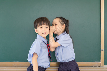 小学生在黑板前讲秘密背景图片