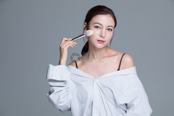 年轻美女手拿化妆刷图片