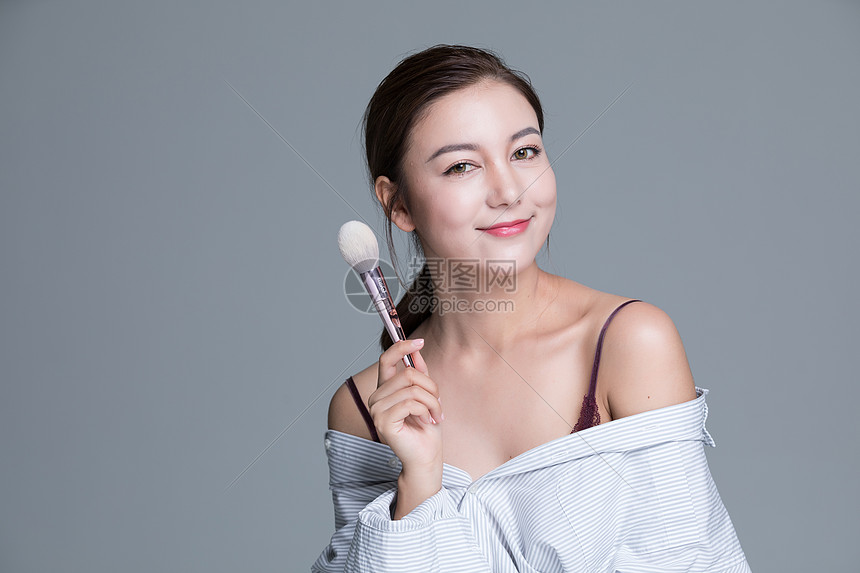 年轻美女手拿化妆刷图片