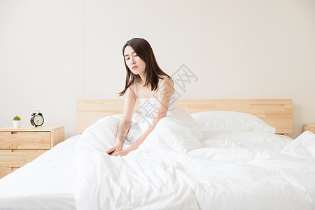 年轻女性醒来坐床上背景图片