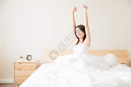 年轻女性起床床上伸展背景图片