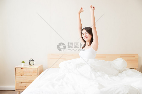 年轻女性起床床上伸展图片