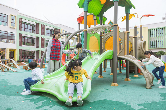 户外幼师带儿童玩滑滑梯图片