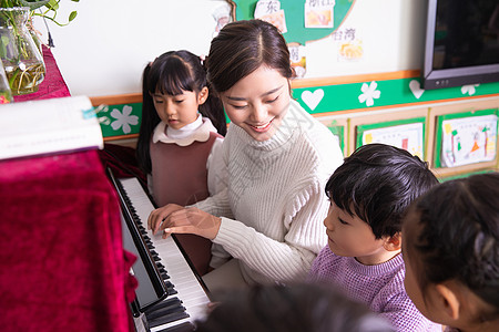 钢琴老师幼儿园老师带小朋友弹钢琴背景