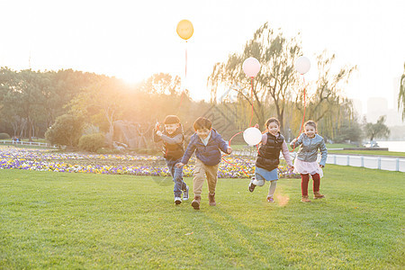 夕阳下拿着气球的儿童们背景图片