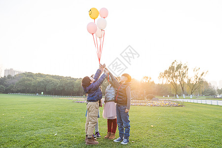 夕阳下儿童们共同放气球图片