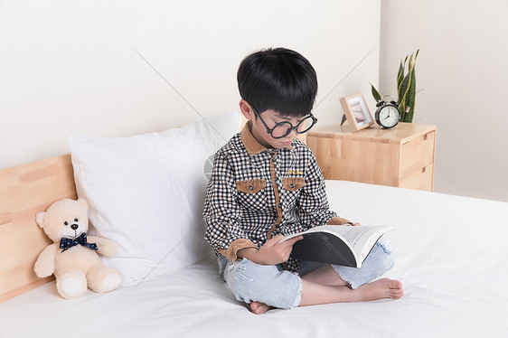 在床上看书的小男孩图片