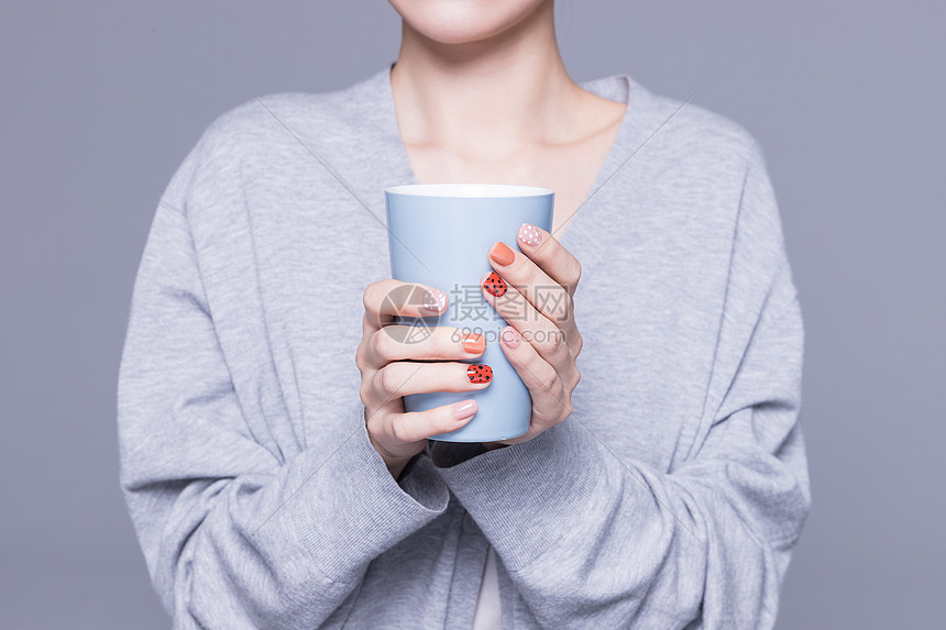 女性美甲手捧水杯特写图片