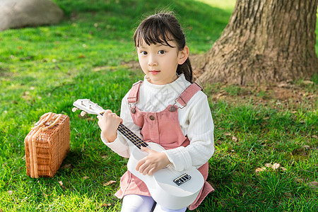 女孩在草坪上弹吉他高清图片